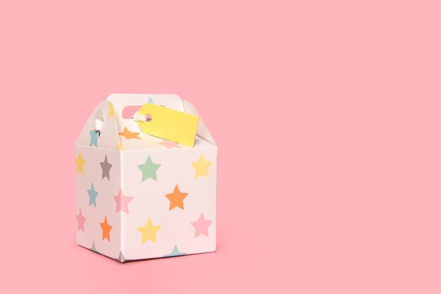 Caja de regalo de cartón con etiqueta en un fondo rosado con espacio para copiar