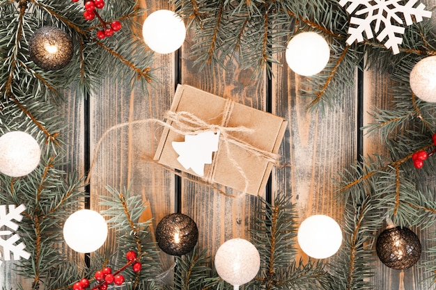 Caja de regalo de cartón de Navidad Kraft atada con cuerda de yute en marco de guirnalda de rama de árbol de Navidad con bombillas de bola de hilo