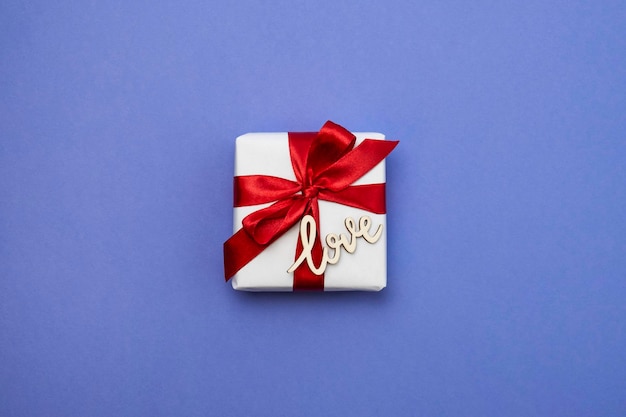 Caja de regalo con cinta roja sobre fondo violeta