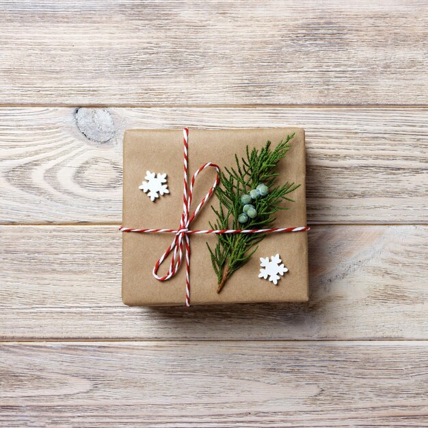 Caja de regalo con cinta roja sobre superficie de madera blanca