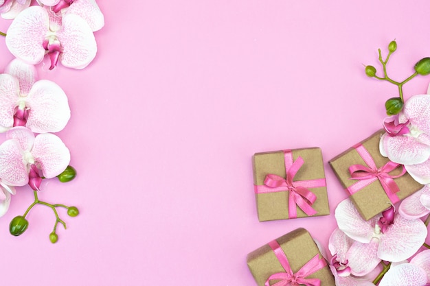 Caja de regalo con una cinta rosa y flores de orquídeas