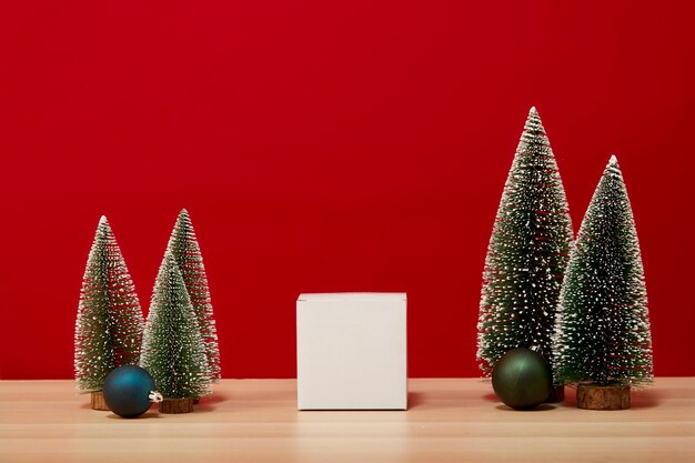 Caja de regalo de composición de árbol de Navidad Adornos de Navidad sobre una mesa de madera de fondo rojo de la pared. para las vacaciones de año nuevo o Feliz Navidad de espacio libre para su decoración Copie el espacio para su texto