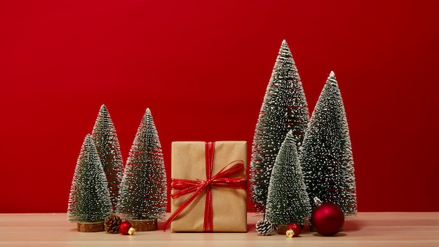 Caja de regalo de composición de árbol de Navidad Adornos de Navidad sobre una mesa de madera de fondo rojo de la pared. para las vacaciones de año nuevo o Feliz Navidad de espacio libre para su decoración Copie el espacio para su texto