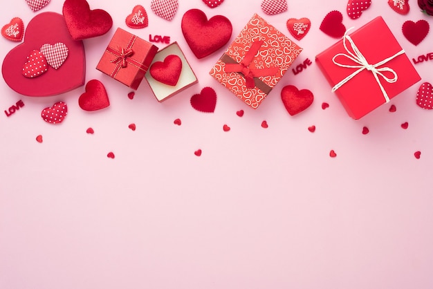 Caja de regalo y corazón rojo sobre fondo rosa con espacio de copia para boda de amor o día de San Valentín.