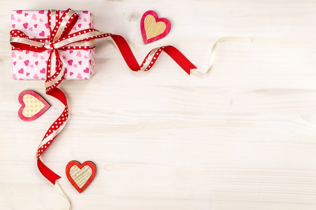 Caja de regalo con corazones y cinta sobre fondo de madera