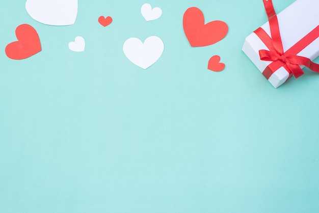 Caja de regalo, corazones rojos y blancos sobre fondo azul pastel. Concepto de día de San Valentín o ceremonia de boda