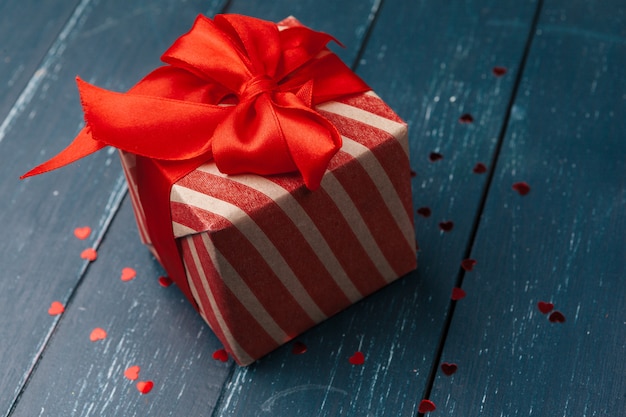 Caja de regalo con corazones rojos en mesa de madera