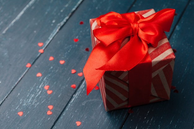 Caja de regalo con corazones rojos en mesa de madera