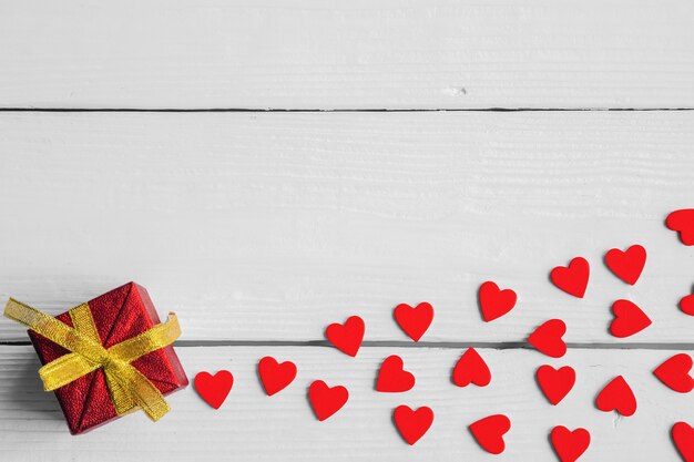 Caja de regalo y corazones rojos sobre fondo claro de madera, concepto de día de San Valentín