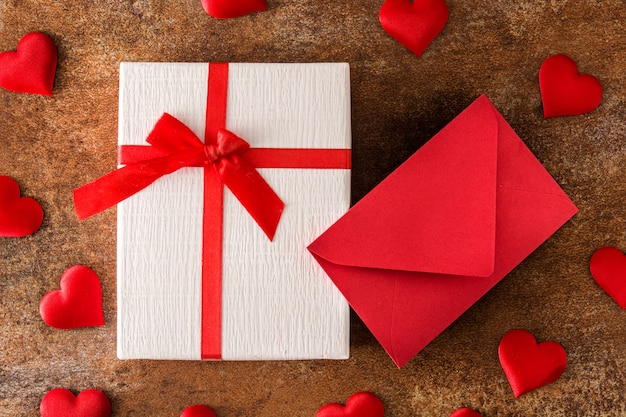 Caja de regalo con corazones y sobre de papel rojo sobre superficie oxidada