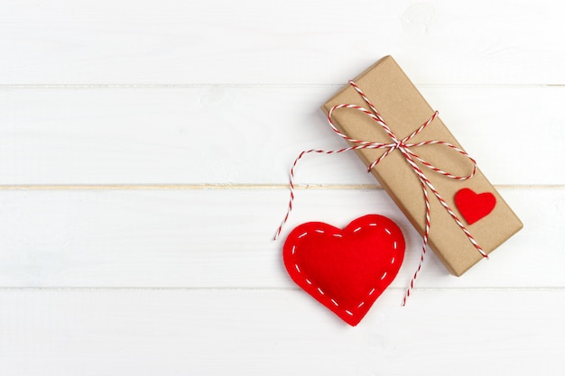 Caja de regalo con corazones de tela en mesa de madera negra.