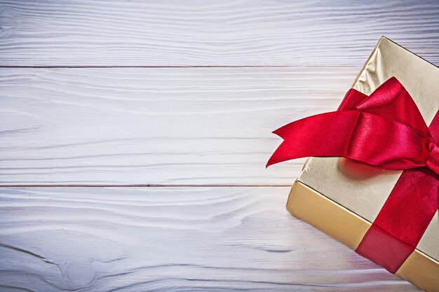 Caja de regalo de cumpleaños con cinta de raso rojo en el concepto de vacaciones de tablero de madera