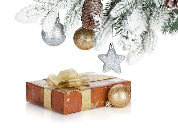 Caja de regalo y decoración navideña bajo el abeto nevado. Aislado sobre fondo blanco