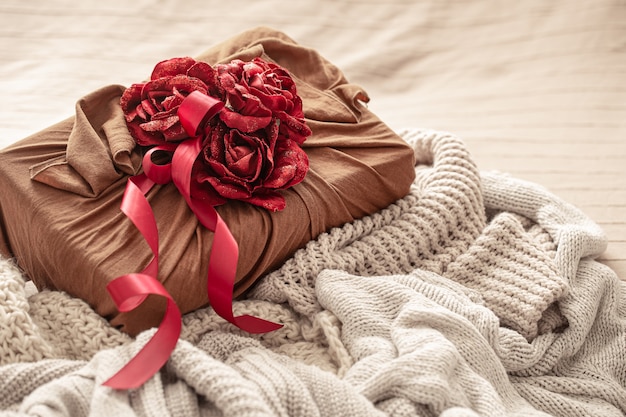 Caja de regalo decorada con cintas y rosas decorativas sobre artículos de punto. Envoltorio de regalo original para San Valentín.