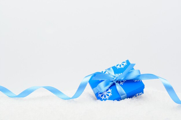 Caja de regalo decorativa con cinta azul sobre la nieve