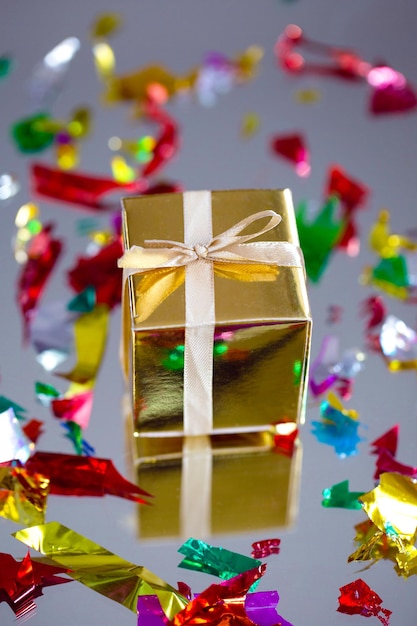 Caja de regalo dorada con cinta dorada, lazo para cumpleaños, Navidad, día de San Valentín, concepto del día de la madre. sobre fondo gris diseño actual