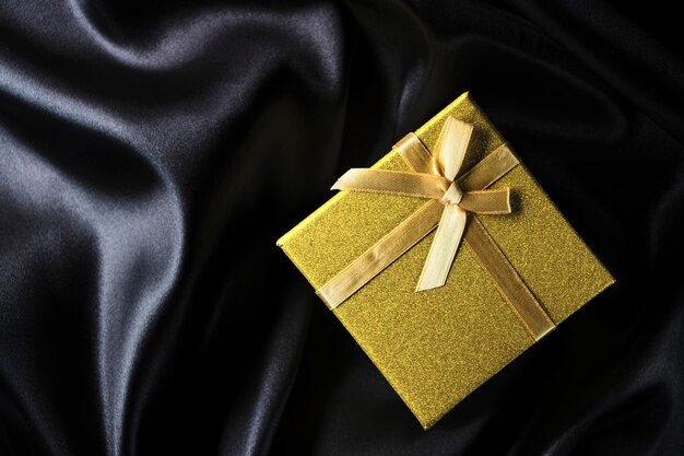 Caja de regalo dorada con fondo de lazo con tela de seda negra