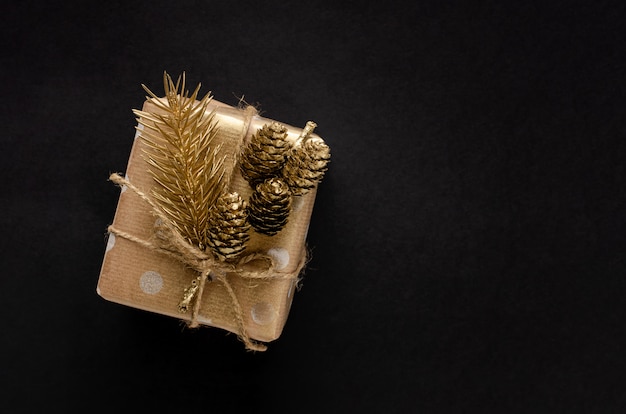Caja de regalo envuelta en papel artesanal con abeto dorado y cono en negro
