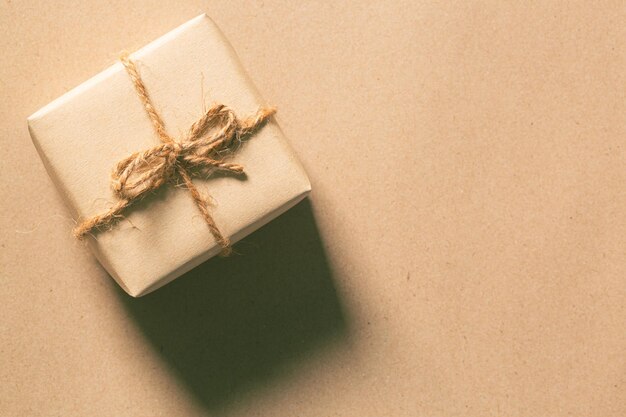 Caja de regalo envuelta en papel artesanal con cinta dorada y estrellas sobre piedra gris