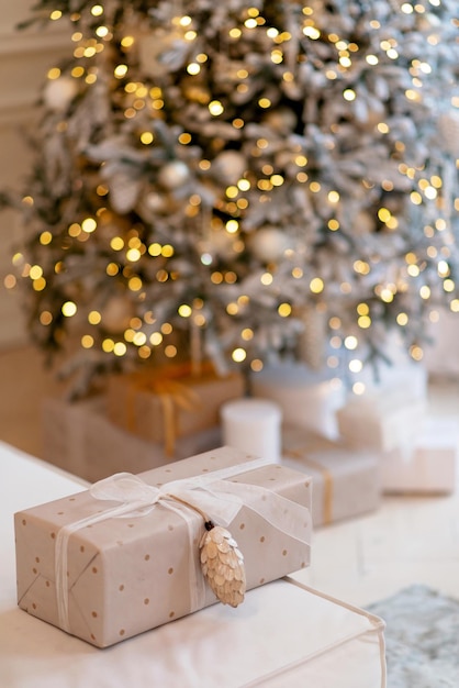 Caja de regalo envuelta en papel de regalo con piña sobre fondo de luces de año nuevo árbol de navidad bokeh. Copiar el espacio. Enfoque selectivo suave.