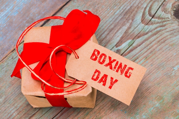 Caja de regalo y etiqueta con un texto: día del boxeo, sobre fondo de madera.