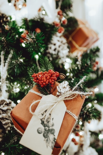 Caja de regalo festiva en el árbol de Navidad, decoraciones para el hogar de año nuevo, envoltura de papel de regalos de Santa, detalles festivos, celebración tradicional. Copie el espacio. Espíritu navideño y ambiente de año nuevo.