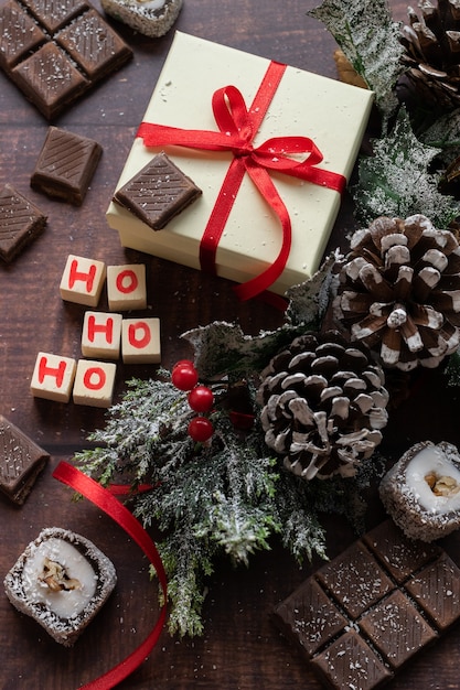 Caja de regalo festiva de Navidad y dulces con decoraciones de temporadas sobre fondo de madera