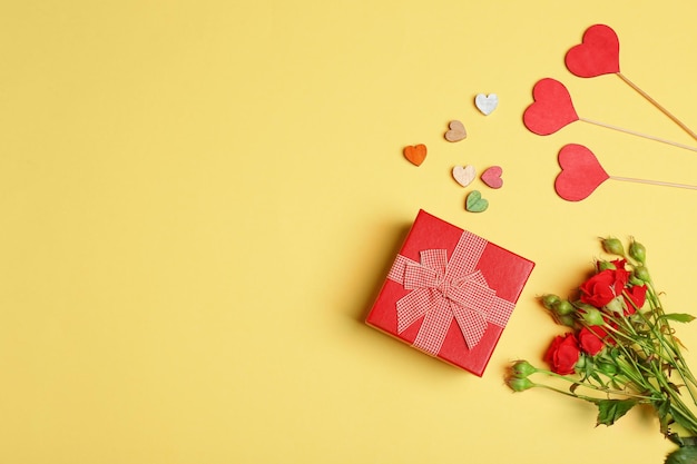 Caja de regalo flores y corazones decorativos sobre fondo de color