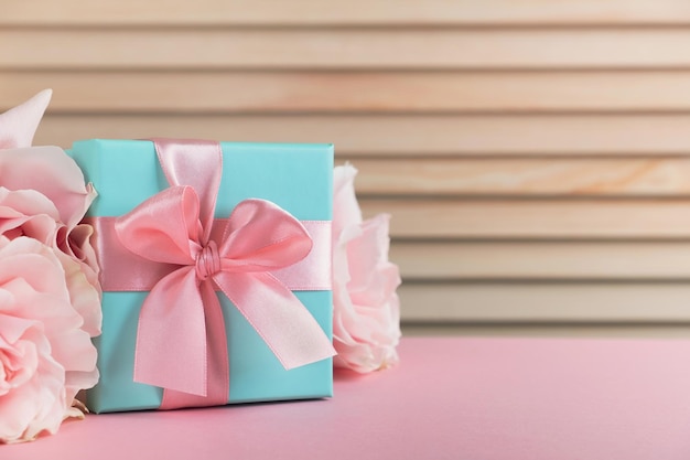 Caja de regalo con flores rosas en mesa rosa Concepto de primavera del día de la madre