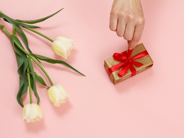 Caja de regalo con flores de tulipán sobre un fondo rosa