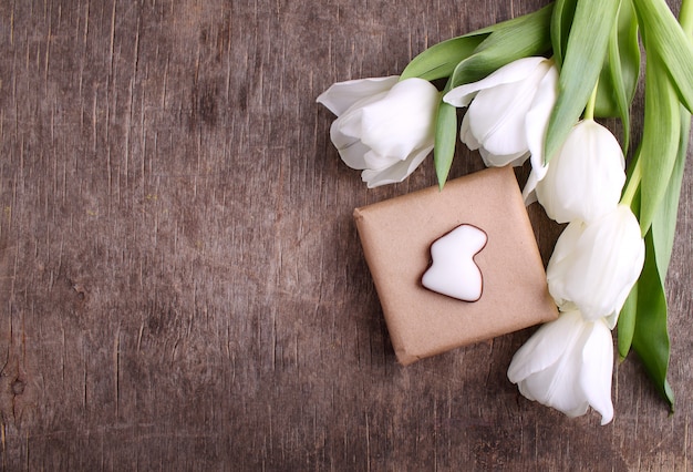 Caja de regalo con flores (tulipanes blancos) sobre fondo de madera rústico