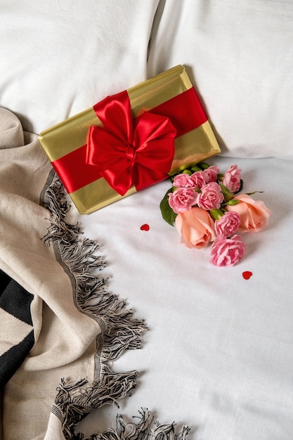 Una caja de regalo y flores yace en la cama temprano en la mañana. Contenido para lunamieleros y enamorados para San Valentín.