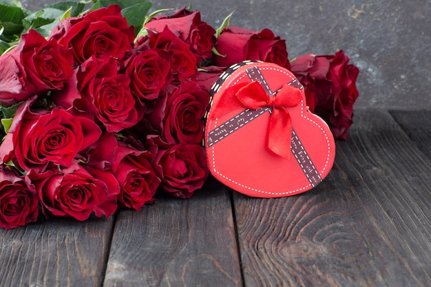 caja de regalo en forma de corazón y ramo de rosas rojas