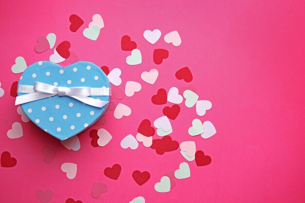 Caja de regalo en forma de corazón sobre fondo rosa