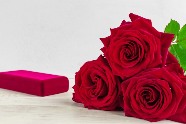 Caja de regalo de joyería y bautiful rosas rojas sobre fondo de madera.