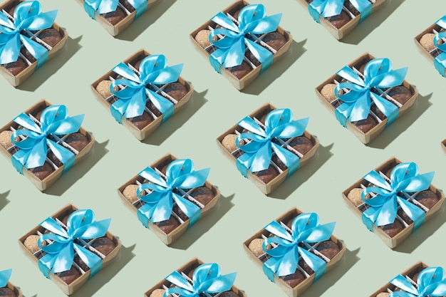 Caja de regalo con lazo de cinta con dulces artesanales de chocolate en el interior sobre fondo verde