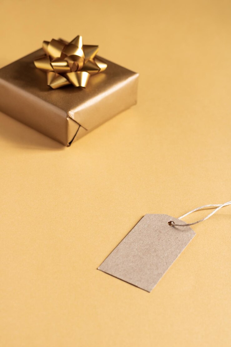 Foto caja de regalo con lazo y una etiqueta vacía en fondo amarillo