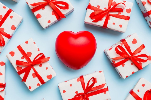caja de regalo con lazo rojo y corazón rojo en fondo de color vista superior colocación plana