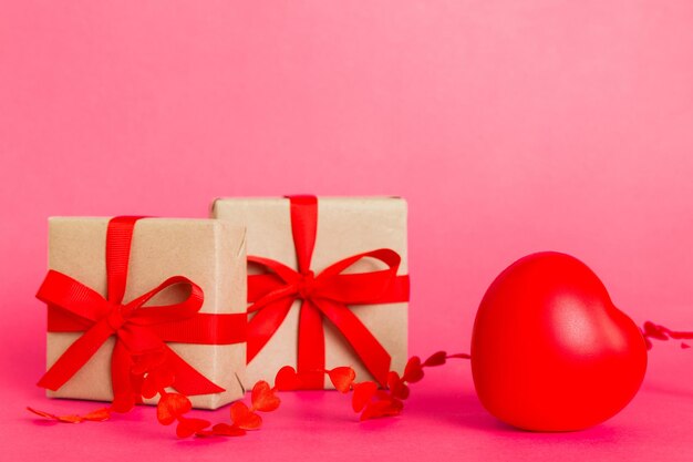 Foto caja de regalo con lazo rojo y corazón rojo sobre fondo de color vista en perspectiva endecha plana