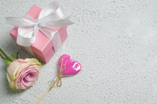 Caja de regalo con lazo rosa, piruleta y gypsophila.