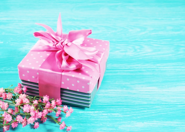 Una caja de regalo con un lazo rosa sobre un fondo de madera, copia del espacio de texto.