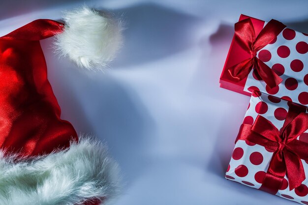 Caja de regalo llena de gorro de Papá Noel rojo sobre fondo blanco.