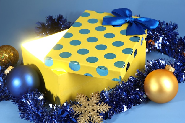 Caja de regalo con luz brillante sobre fondo azul.