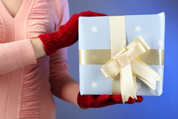 Foto caja de regalo en mano femenina sobre fondo de color