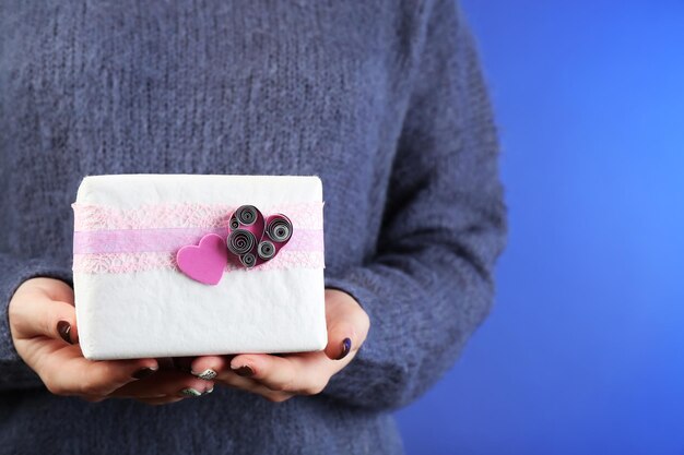 Caja de regalo en mano femenina sobre fondo de color