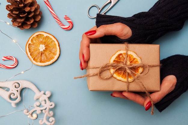 Caja de regalo en manos y adornos navideños.