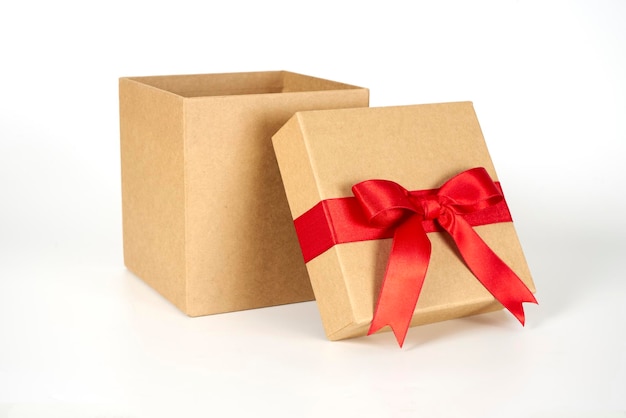 Caja de regalo marrón con una cinta roja sobre un fondo blanco.