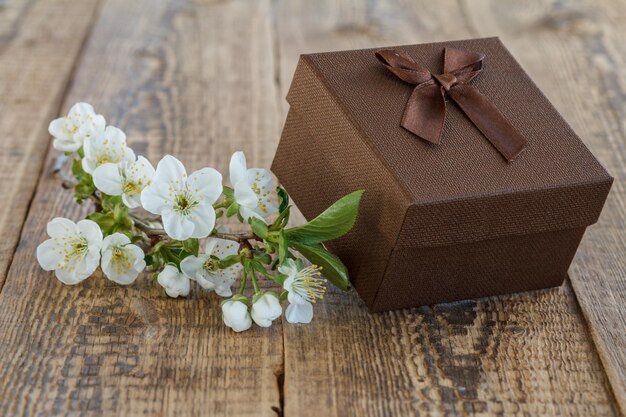 Caja de regalo marrón decorada con flores de jazmín en viejas tablas de madera.