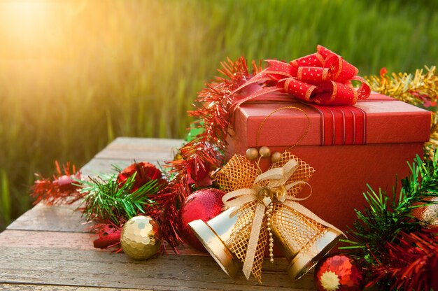 Caja de regalo de Navidad con adornos en la mesa de madera en puesta de sol