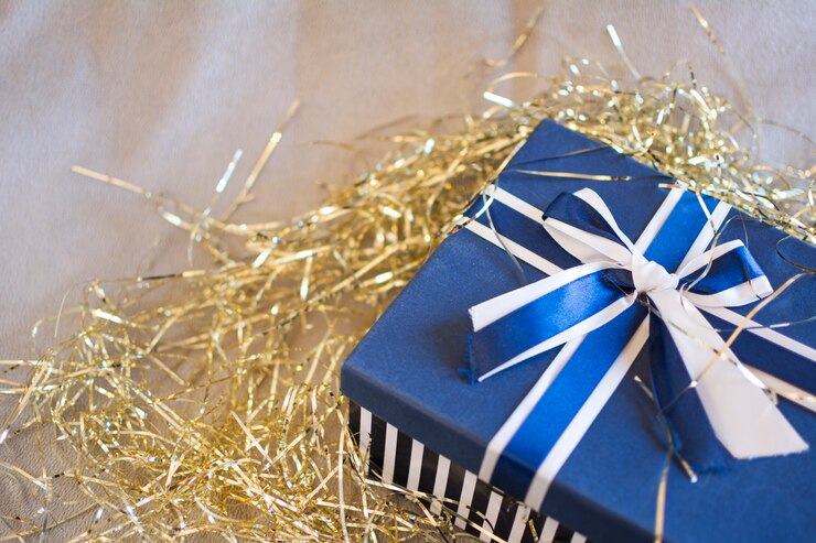 Caja de regalo de Navidad azul con lazo azul y blanco y adornos de oro. Copyspace a la izquierda.